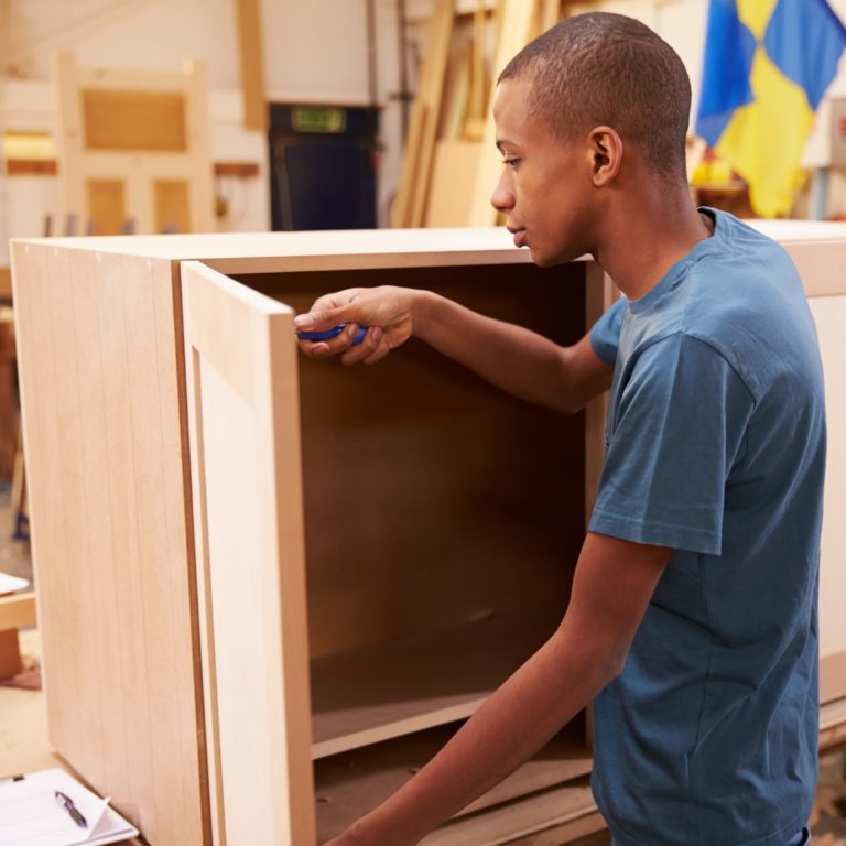 Apprentice Building Furniture In Carpentry Workshop